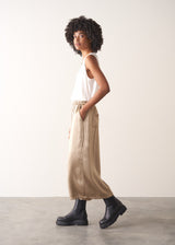 Woman wearing a white sleeveless top and champagne satin wide-leg trousers against a plain background