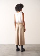 Woman wearing a white sleeveless top and champagne satin wide-leg trousers against a plain background