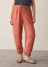 Woman wearing terracotta linen trousers with beige sandals