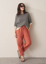 Woman wearing terracotta linen trousers with stripe top and sunglasses