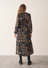 A woman wearing a dark floral satin midi dress with waist tie and button up detail and black chunky boots