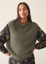 A woman wearing a long-sleeve, dark floral midi dress with a tie waist, set against a plain off-white studio background.