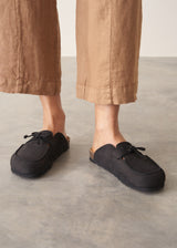 Pair of black moccasin slipper shoes on a grey concrete surface