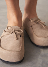 Pair of beige moccasin slipper shoes on a grey concrete surface
