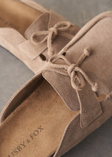 Pair of beige moccasin slipper shoes on a grey concrete surface