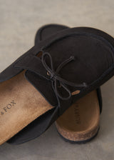 Pair of black moccasin slipper shoes on a grey concrete surface