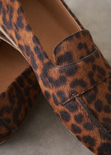 Pair of leopard print loafers on a grey surface