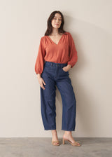 Woman wearing a terracotta cotton blouse with embroidered detail and blue jeans