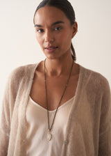 Women wearing a smokey grey crystal beads, finished with white, quartz heart pendant, with a satin blouse and oatmeal cardigan