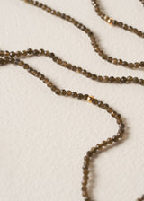 Close up of smokey grey crystal beaded necklace, on a beige background