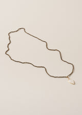 A smokey grey crystal bead necklace, finished with white, quartz heart pendant, on a beige background