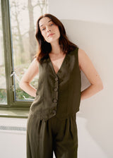 Model wearing a matching set - khaki green linen blend waistcoat and trousers - against beige background