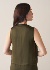 Woman wearing a green satin blend waistcoat with matching green trousers against a beige background