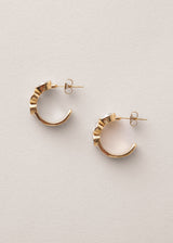 Pair of crystal adorned open hoop earrings on beige background