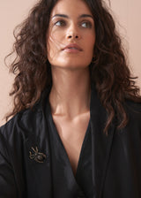 Women wearing a crystal adorned spider brooch on black top