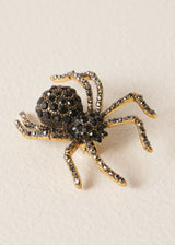 Crystal adorned spider brooch on a beige background
