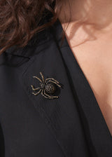 Close up of model wearing a crystal adorned spider brooch on black top