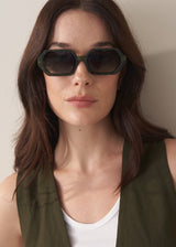 Woman wearing dark sunglasses with a neutral background