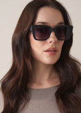 Woman wearing dark sunglasses with a neutral background