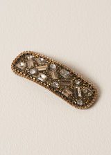 Gold crystal embellished hair clip on beige background