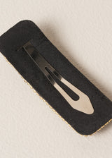 Back of gold crystal embellished hair clip on beige background