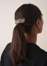 Women wearing a gold crystal embellished clip with her hair tied up, styled with a black jumper