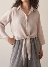 Woman wearing nude tie-front linen shirt with striped wide leg trousers.