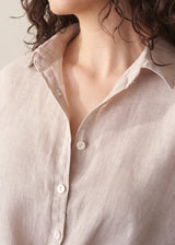 Woman wearing nude tie-front linen shirt with striped wide leg trousers.