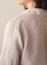Woman wearing nude tie-front linen shirt with striped wide leg trousers.