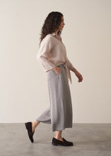 Woman wearing nude tie-front linen shirt with striped wide leg trousers.