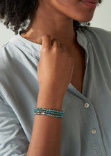 Woman wearing three teal crystal bracelets with blue blouse