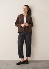 Woman wearing a brown faux suede jacket and dark jeans