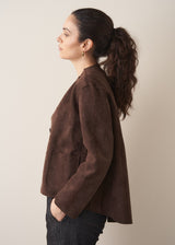 Woman wearing a brown faux suede jacket and dark jeans