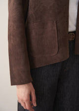 Woman wearing a brown faux suede jacket and dark jeans