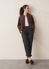 Woman wearing a brown faux suede jacket and dark jeans