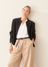 Woman wearing black faux suede boxy jacket and beige cropped trousers