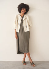 Woman wearing a khaki satin midi dress with khaki strappy sandals.