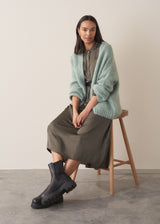 Woman wearing a long dark green satin dress