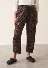 A woman wearing leopard-print velour trousers with a drawstring waist, paired with a white blouse and black slip-on shoes.