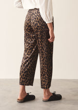 A woman wearing leopard-print velour trousers with a drawstring waist, paired with a white blouse and black slip-on shoes.