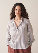 Woman wearing striped cotton shirt with ruched sleeves and frilled collar
