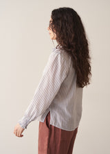 Woman wearing striped cotton shirt with ruched sleeves and frilled collar
