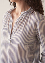 Woman wearing striped cotton shirt with ruched sleeves and frilled collar