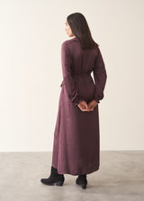 Woman wearing long sleeve plum satin button up dress with waist tie