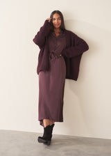 Woman wearing long sleeve plum satin button up dress with waist tie