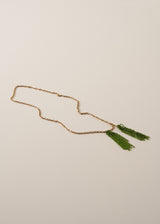 A long, chunky chain necklace with two pendants made of colourful green crystal strands, photographed on a beige background