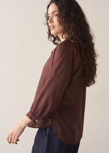 Woman wearing a sheer brown cotton shirt with blue jeans