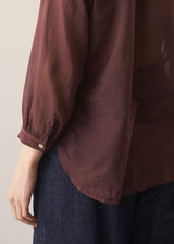 Woman wearing a sheer brown cotton shirt with blue jeans