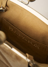 Close-up of the interior of a clutch bag showing a tan fabric lining with the debossed brand name 'BUSBY & FOX' and silver-tone metal hardware.