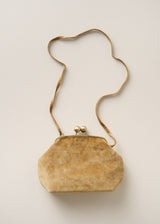 A small vintage-style clutch bag in textured tan suede or velvet with a matching wavy shoulder strap and a kiss-lock clasp, photographed on a light beige background.